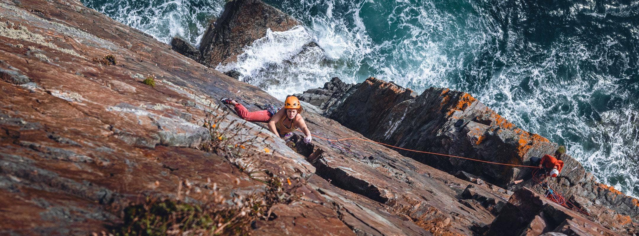 Female climbing up sea cliffs  