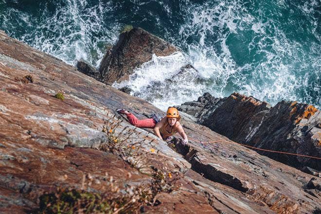 Female climbing up sea cliffs  