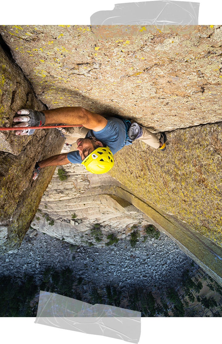 Photo of Erik climbing taken from above, with the rock-scattered ground stretching out far below. He looks calm but focused. 