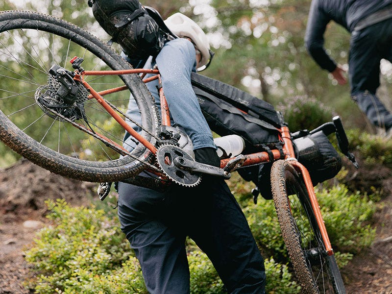 Cyclist carrying their bike uphill