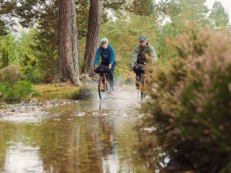 Two cyclists fording a flooded path