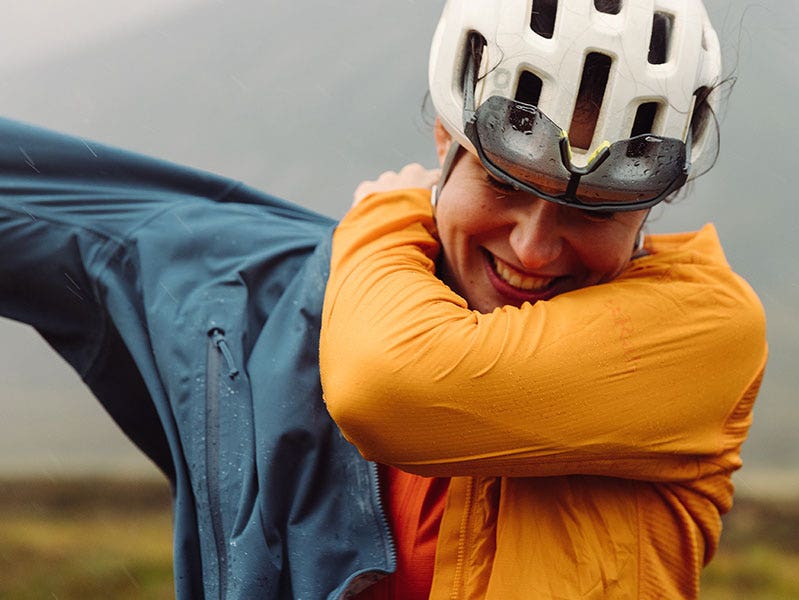 Cyclist pulling on a waterproof layer